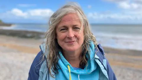 Woman with grey/blonde hair looking at camera